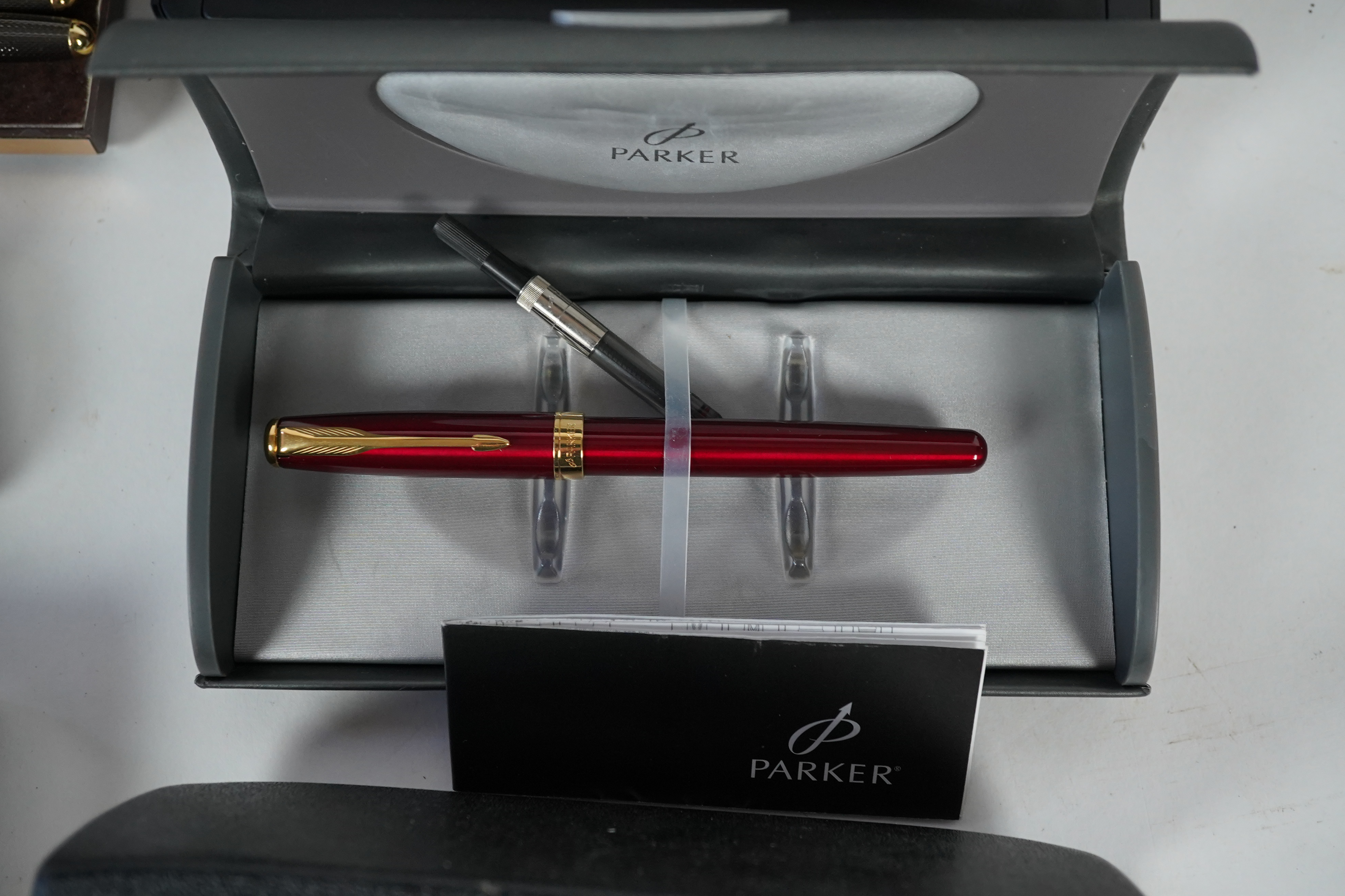 A cased Parker duofold ballpoint pen, a cased Parker Sonnet lacquer ruby red fountain pen, a Dunhill gold plated fountain pen and various fountain pens and ballpoint pens including Parker, Sheaffer, Quill, etc.